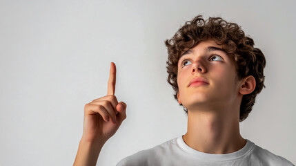 A young man with a thoughtful expression points upward against a white background.