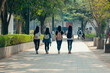 © romanets_v - Group of four friends walking on campus pathway with backpacks in spring