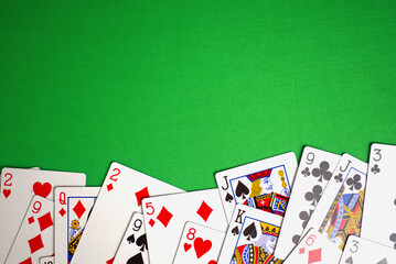 top view of random playing cards on green table. copy space green background