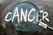 © GoodIdeas - Cancer - learn, study and inspect it. Taking a closer look at cancer. A magnifying glass enlarging word 'cancer' written on a blackboard ,3d illustration