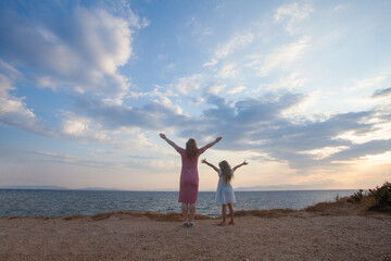 Happy mother and daughter walking on beach and having fun outdoors