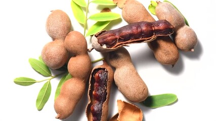 Sticker - Tamarind fruit isolated on white background. Tamarind tropical pods with leaves rotating. Fresh Tamarind pods with leaves (Tamarindus indica, Indian date), healthy vegan food close up, from above. 