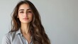 © Robert Kneschke - Confident Middle Eastern woman in her 20s with long hair in a professional attire, exuding poise and elegance against a neutral background.
