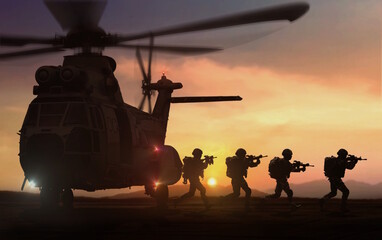 silhouette of military special force unit on a mission with helicopter in background under sunset sky