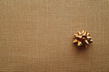 Poster - A solid textured background imitating gift wrapping paper featuring a small golden bow in the corner, suitable for festive occasions. Generative AI