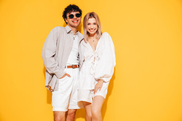 Canvas Print - Happy beautiful romantic teenage couple. Smiling handsome caucasian man and young woman in summer clothes posing in studio, hugging sharing emotions, cheerful and happy. Isolated on yellow