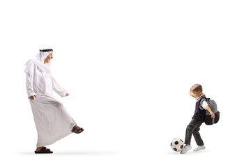 Arab man in traditional robe playing football with a boy