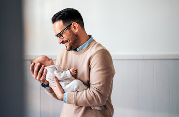 Wall Mural - Portrait of young father holding his newborn baby. Fatherhood love single dad fathers day concept.