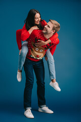 A cheerful couple embraces the festive season while wearing playful sweaters and sharing joyful moments.