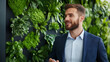 © Kornwit - A business person in an eco-friendly office space, discussing sustainability strategies with colleagues, green plants in the background