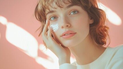 Portrait of pleased young lady touching cheek with hand. She putting cream on face skin indoor