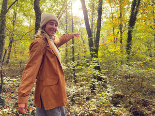 A woman wearing a brown jacket and a white hat is pointing to the sky