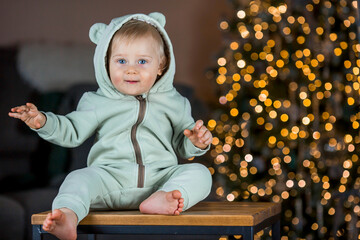 Family and children. A beautiful blond boy of 1 year old on the background of a Christmas tree. The concept of celebrating Christmas and New Year.