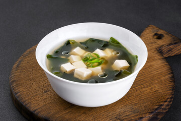 Seaweed soup with tofu on wooden board.