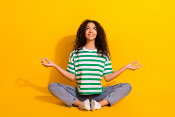 Wall Mural - Full size photo of pretty young girl meditate look up empty space wear striped t-shirt isolated on yellow color background