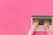 © Mutimul - Child's Hands Typing on a Laptop with Pink Background