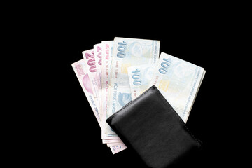 100 and 200 Turkish Lira banknotes and wallet isolated on black background. Turkish lira falling in value. Economy idea concept. Paper money. 