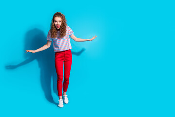 Wall Mural - Joyful woman in colorful casual outfit posing with excitement against a vibrant blue background.