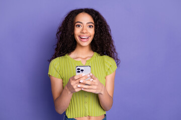 Canvas Print - Photo portrait of pretty teen girl hold gadget excited wear trendy green outfit isolated on purple color background