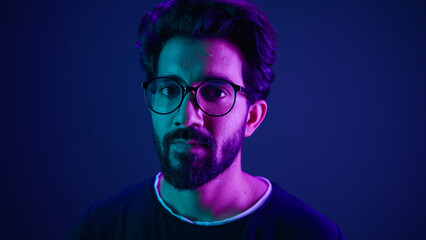 Close up portrait neon ultraviolet background Indian man guy developer coder smart hacker clever coding computer engineer showing gesture think about it thinking hard brain mental ponder IQ remember