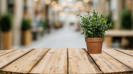 Canvas Print - Empty round wooden table with a potted plant standing on it and blurred restaurant in the background