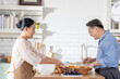 © ultramansk - A woman prepares fresh vegetables in a cozy kitchen, while a man assists in the background. The scene emphasizes a warm and healthy lifestyle with a focus on fresh produce and home cooking.