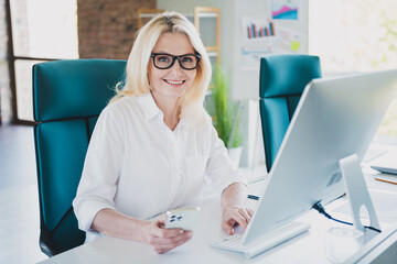 Wall Mural - Photo of young blonde hair business woman using smartphone sitting workplace with computer having video conference