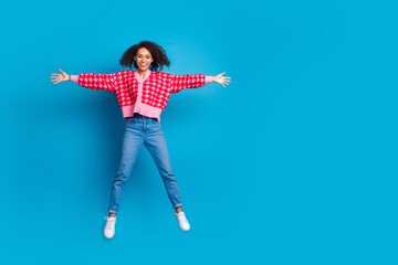 Wall Mural - Portrait photo of american beautiful girl with curly hair wearing red shirt jumping star symbol isolated on blue color background