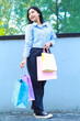 © M Alfan Setyawan - vertical shoot of smiling asian woman holding shopping bag walking in outdoors around city mall building
