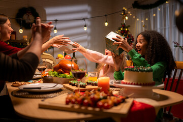 Grandfather, parents, and the teenage girls are all having dinner together at home on Christmas night