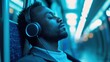 © Art Fusion - Black man with headphones sitting in the subway, relaxed and listening to music, with soft blue light reflecting from the windows, background in blurred zone