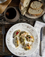 Wall Mural - A plate of homemade dumplings or pierogi served with a cup of dark liquid and slices of bread on a rustic wooden table