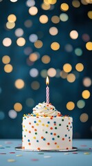 Birthday cake with lit candle standing on blue table with confetti