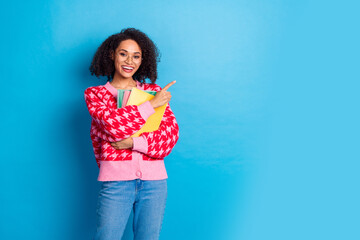 Sticker - Portrait photo of girl with curly hair wearing eyeglasses hold books direct finger education courses ad isolated on blue color background