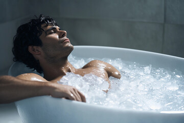 Latin american man in a ice bathtub, athlete training endurance, repair of muscules, ice bath pod