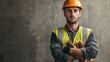 © Keopaserth - construction worker wearing yellow safety vest and orange hard hat stands confidently with arms crossed against concrete wall. serious expression adds to professional atmosphere