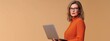 © yj - Happy mature business woman using laptop standing isolated on beige background. Middle aged professional businesswoman ceo executive holding computer.