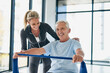 © SensSai/peopleimages.com - Fitness, old man and physiotherapist with band for workout, rehabilitation and healing for injury. Portrait, senior patient and female person with help for physiotherapy, stretching arms and exercise