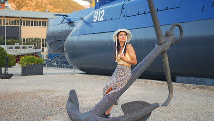 Young attractive fashion model posing sitting on a large ship anchor.