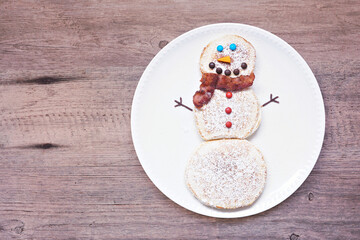 Wall Mural - Cute Christmas Snowman pancakes. Top view against a wood background.