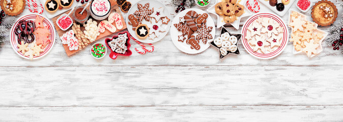 Wall Mural - Christmas holiday cookies and desserts top border. Above view on a white wood banner background. Cookies, tarts, chocolates and hot chocolate tray.