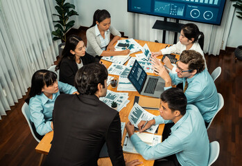 Diverse group of business analyst team analyzing financial data report. Finance data analysis chart and graph dashboard show on TV screen in meeting room for strategic marketing planning. Habiliment