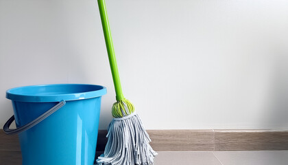 A blue bucket with a green handle sits next to a mop on side position provides copy space for text. background concept isolated white