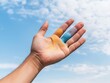 © Adisak - A hand with colorful powders against a bright sky, showcasing creativity and vibrant expression.