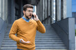 © Tetiana - Upset young male businessman standing outside an office building, talking on the phone emotionally and angrily