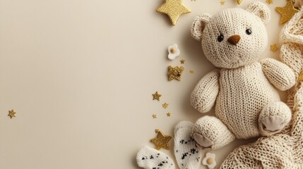 a cute baby teether, a knitted teddy bear, tiny socks, and gold stars are arranged on a soft beige b