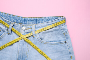 Poster - Jeans and measuring tape on pink background, top view