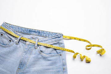 Canvas Print - Jeans and measuring tape on white background, top view