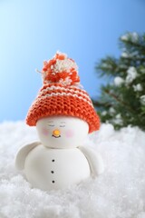 Canvas Print - Cute decorative snowman on artificial snow against light blue background