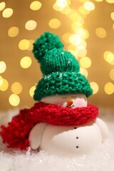 Wall Mural - Cute decorative snowman on artificial snow against blurred lights, closeup